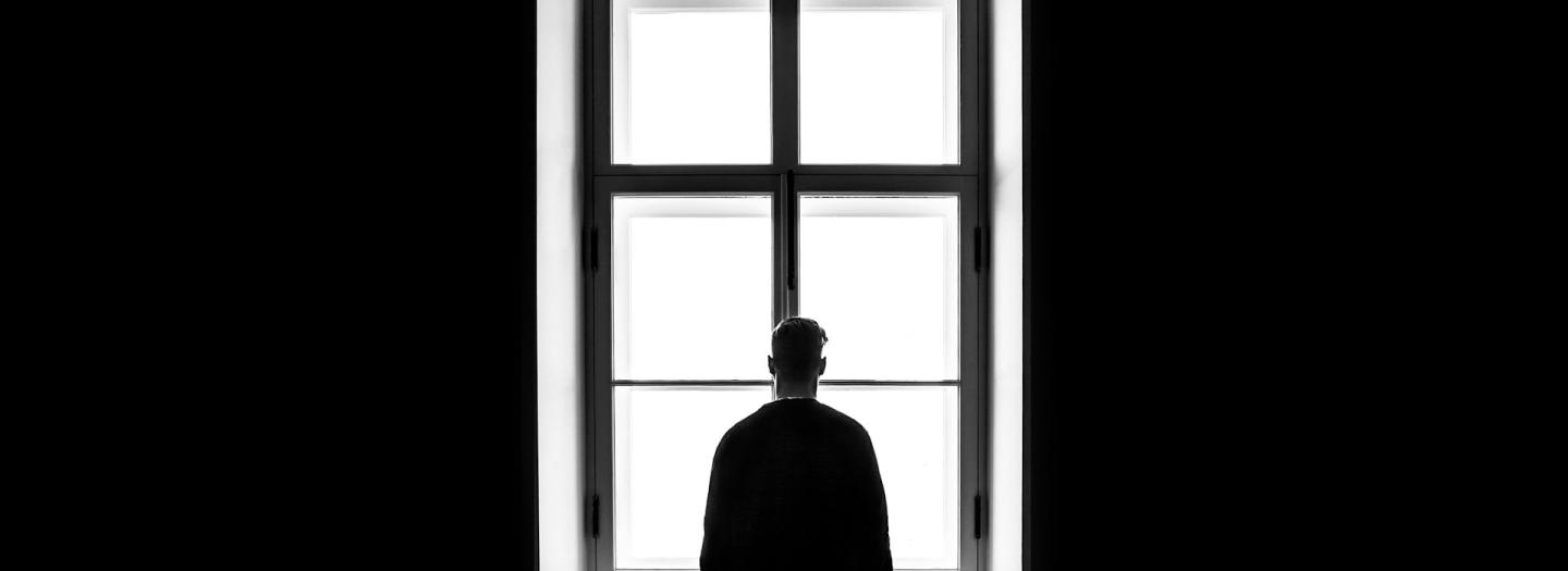 A lonely figure in front of a window indoors